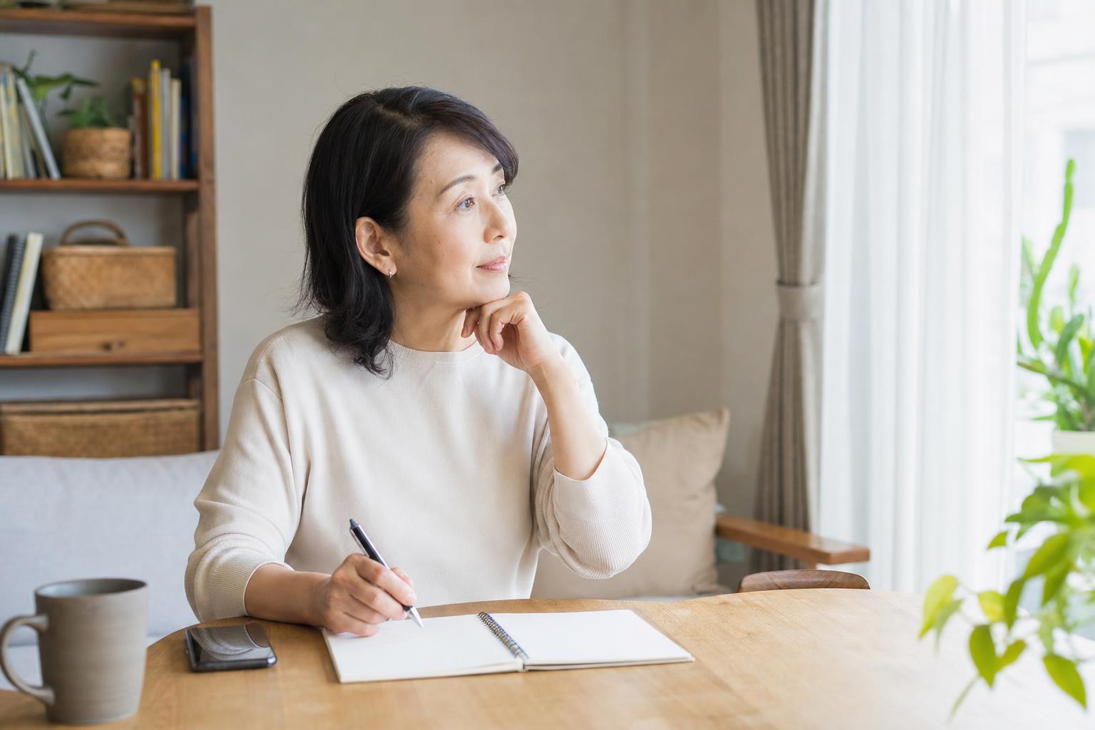 リビングでノートとスマホを前に考えを整理する親世代のイメージ